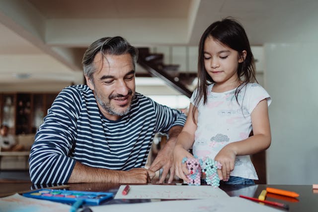 fille-montrant-ses-dessins-et-jouets-a-son-pere
